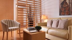 A modern living room with a striped armchair, a beige sofa, a wooden coffee table, and a decorative plant.