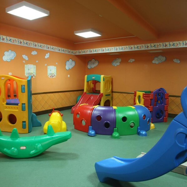 A children's play area with various colorful play structures, including a slide and climbing frames.