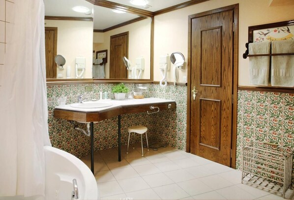 Un baño con lavamanos, espejo y dos barras para toallas.
