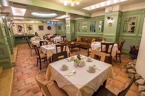 A dining area with tables set for service, a sofa, and a decorative wall. - City Hotel Apollonion (Karpenisi)