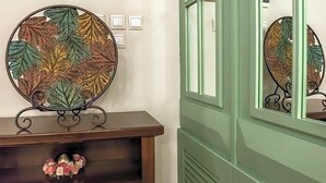 A wall-mounted decorative piece with a circular design and a stand, placed above a wooden console table with a floral arrangement. - City Hotel Apollonion (Karpenisi)