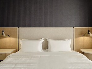 Una habitación de hotel con una cama grande, dos mesitas de noche y dos lámparas colgantes.