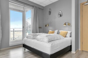 Un dormitorio moderno con una cama grande, un balcón y vistas a la ciudad.