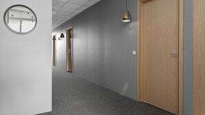 Käytävän lattialla on harmaa matto, seinässä on pyöreä peili ja siellä on myös puinen ovi, jonka kyljessä lukee ’503’.