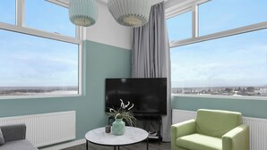 A modern living room with a large TV, a round coffee table, and a green armchair. - Icelandic Apartments (Kópavogur)