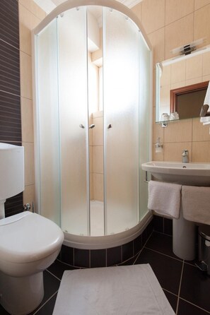 A bathroom with a glass-enclosed shower, a toilet, a sink, and a mirror. - Hotel Porat (Neum)