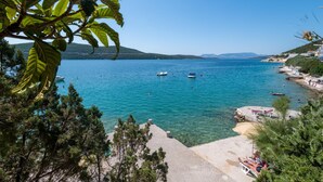 A coastal view with clear blue water, boats, and a beach area with people. - Hotel Porat (Neum)