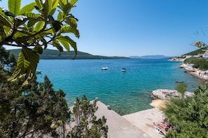 A coastal view with clear blue water, boats, and a beach area with people. - Hotel Porat (Neum)