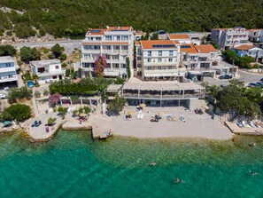 Un pueblo costero con edificios de varios pisos, una zona de playa con tumbonas y agua turquesa cristalina.