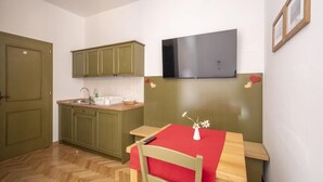 A compact kitchen with green cabinets, a wooden countertop, and a red table with a vase. - Apartment House Berghi Ii (Kranjska Gora)