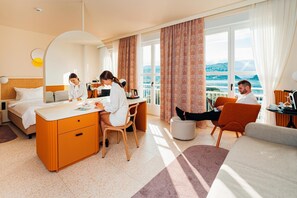 A hotel room with a bed, desk, chairs, and a view of the sea. - Koper (Koper)