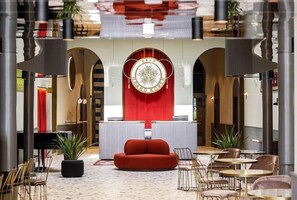 A lobby with a red accent wall, a circular emblem, and a red sofa. - Koper (Koper)