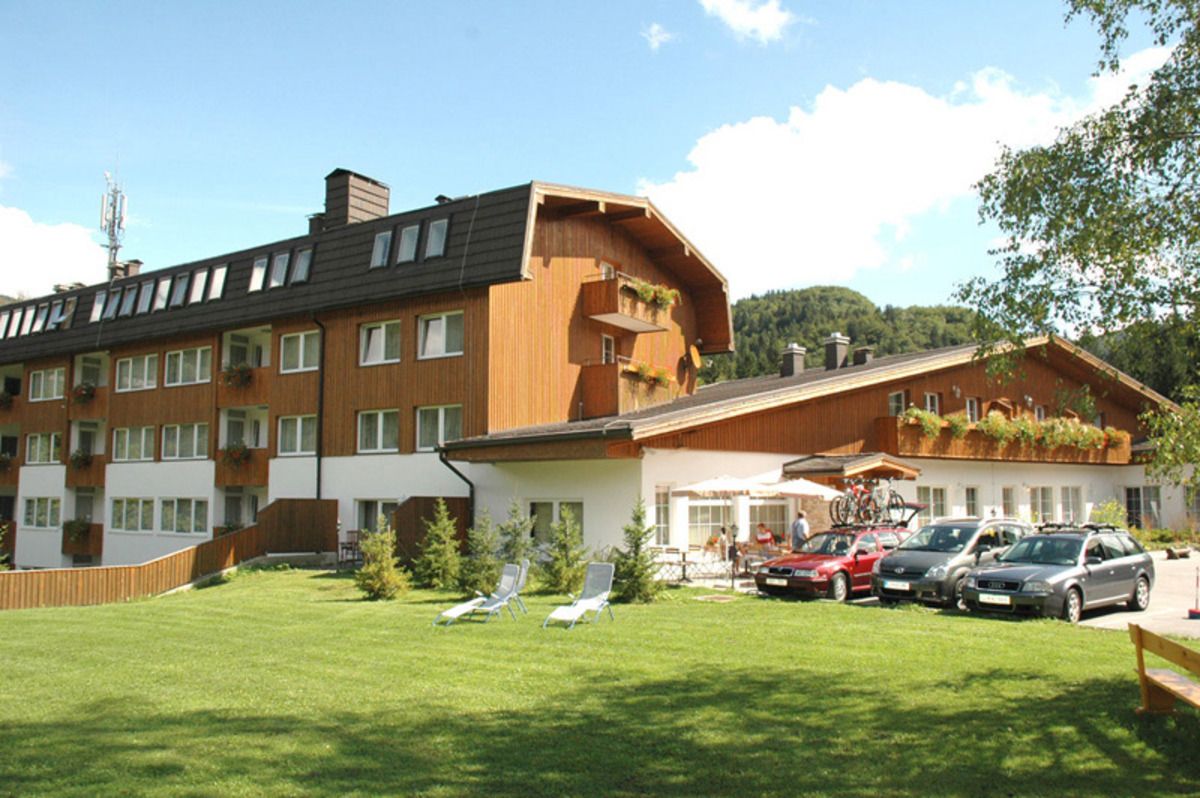 A hotel with multiple floors, outdoor seating, and parked cars.