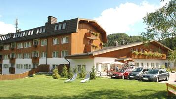 A hotel with multiple floors, outdoor seating, and parked cars.