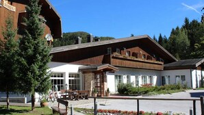 A building with a wooden facade, large windows, and a stone entrance. - Bohinj (Bohinj)