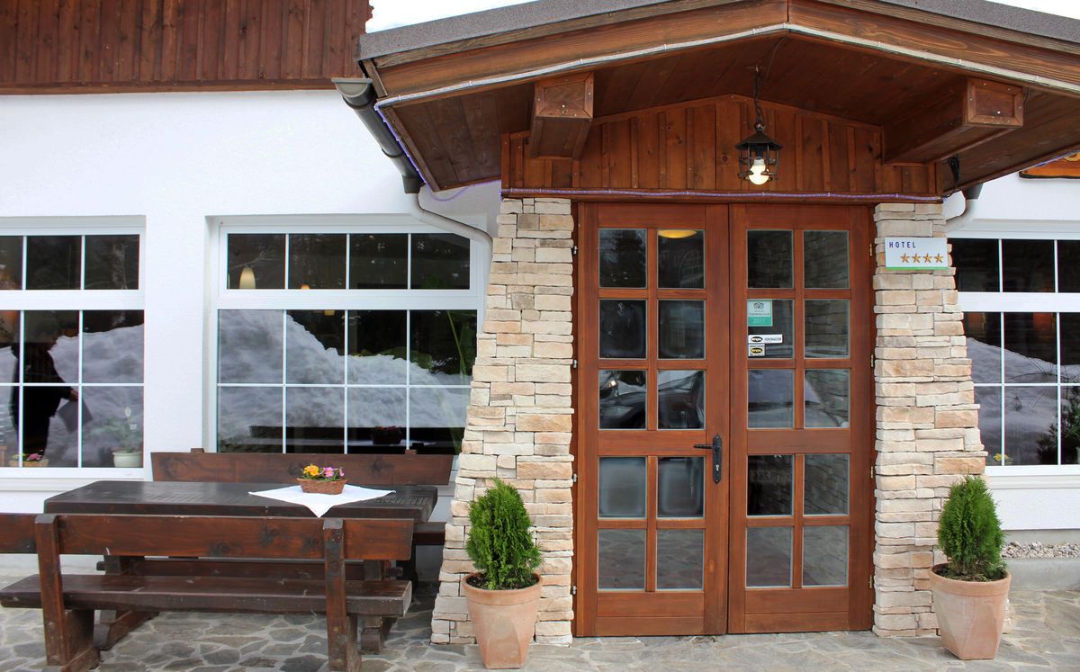 A hotel entrance with a stone facade, wooden door, and a sign indicating a 4-star rating.
