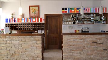 A reception area with a wooden door, a stone wall, a wine rack, and a shelf with various items.