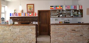 A reception area with a wooden door, a stone wall, a wine rack, and a shelf with various items. - Bohinj (Bohinj)