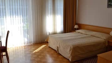 Een hotelkamer met een bed, een bureau, een stoel en een lamp.