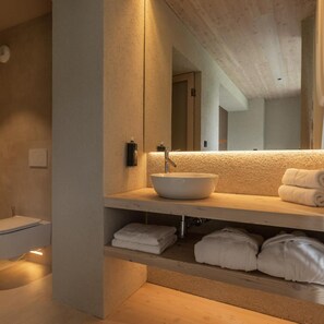 A modern bathroom with a large mirror, a vessel sink, and neatly folded towels on a shelf. - Bohinj (Bohinj)