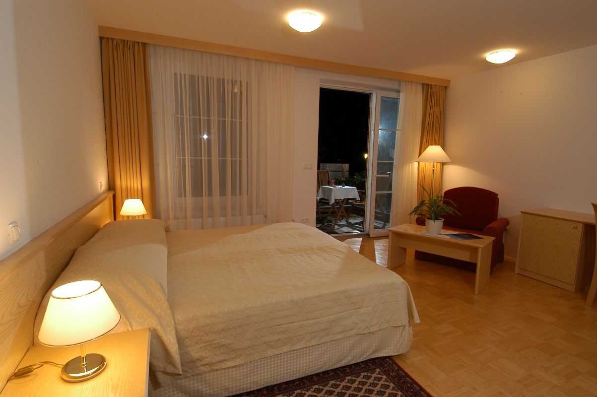 Une chambre d’hôtel comprenant un lit, des lampes de chevet, une petite table avec une lampe, une chaise et un meuble.