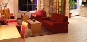 Ein Wohnzimmer mit roten Sofas, einem Holztisch und einem gemusterten Teppich.