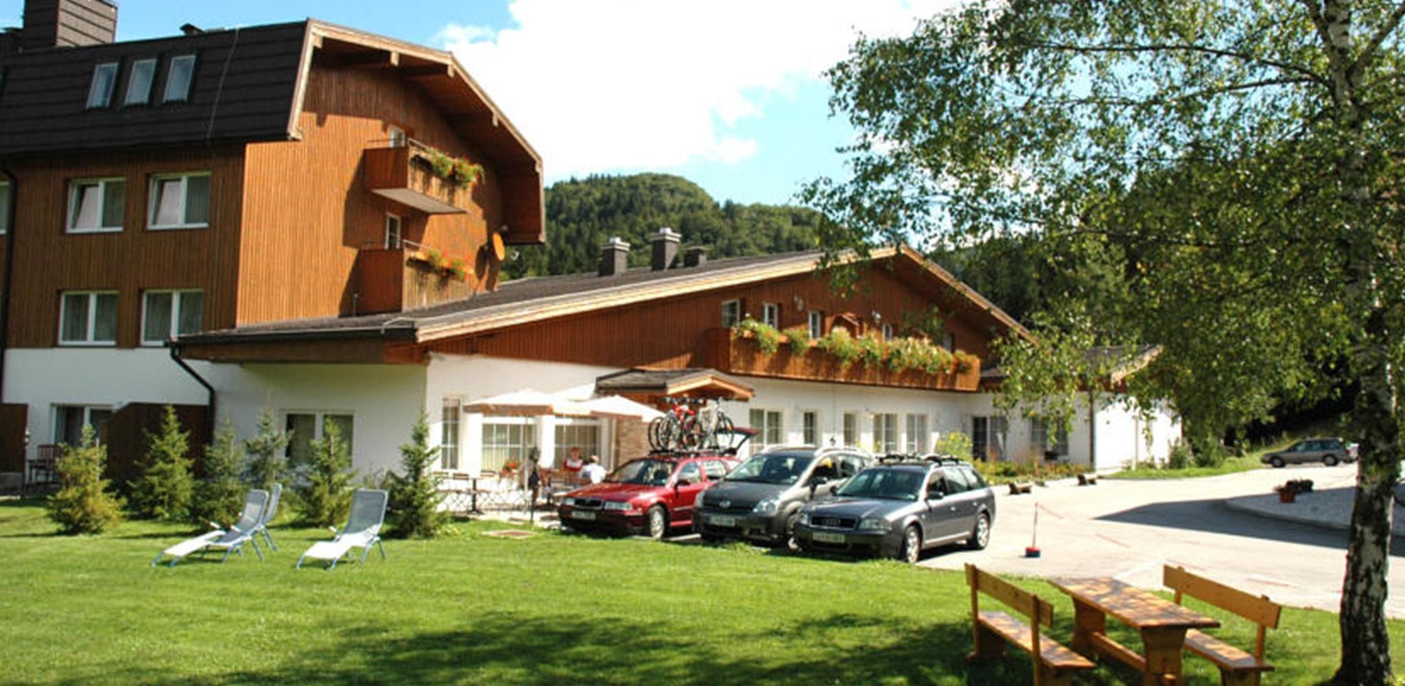 A hotel with a sloped roof, outdoor seating, and parked cars.