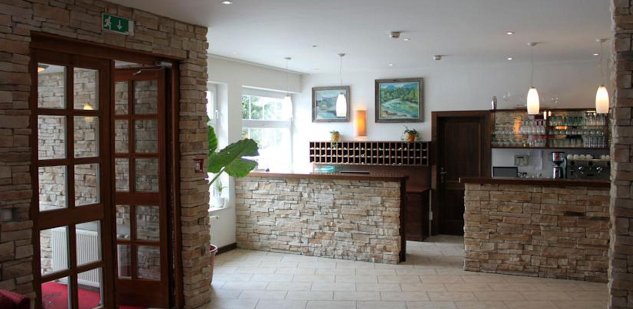 Zona de bar com paredes de pedra, uma porta de madeira e vista para o exterior.