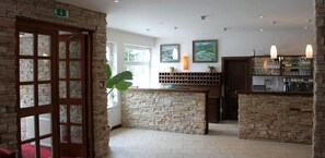 Eine Bar mit Steinwänden, einer Holztür und Blick ins Freie.