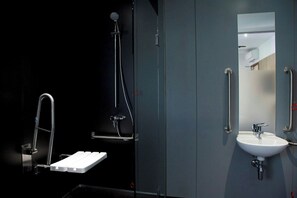 A modern bathroom with a white sink, a mirror, and a shower with a handheld showerhead. - Z Hotel Glasgow (Glasgow)