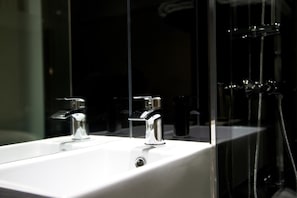 A bathroom with a white sink, two chrome faucets, and a glass shower enclosure. - Z Hotel Glasgow (Glasgow)