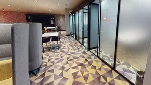 Ein moderner Büroraum mit einem geometrisch gemusterten Boden, einem Konferenztisch und Glaswänden.