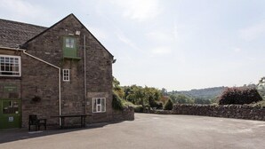 A stone building with a green door labeled "Dovetailed Bar" and a small outdoor seating area. - The Izaak Walton Country House Hotel (Ashbourne)