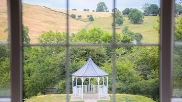 Ein Pavillon in einer üppigen, grünen Landschaft, sichtbar durch ein fenster mit Gittermuster.