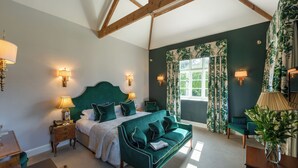 Ein Schlafzimmer mit einem großen Bett, grünen Polstermöbeln und einem Fenster mit Vorhängen.