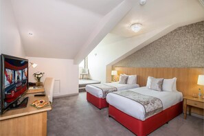 Une chambre d’hôtel avec deux lits, une télévision, un bureau avec un ordinateur portable et une petite table avec des pâtisseries.