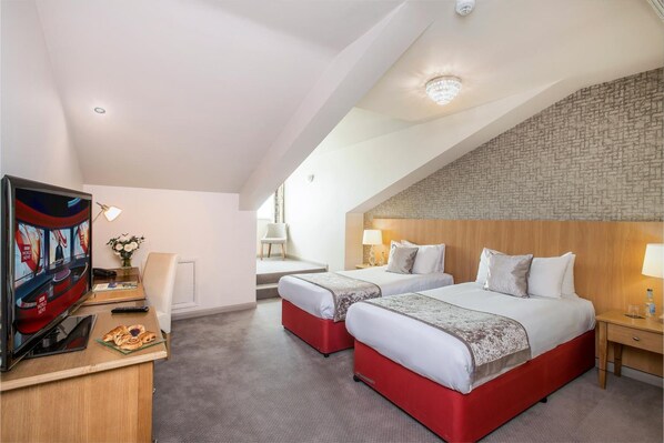 Une chambre d’hôtel avec deux lits, une télévision, un bureau avec un ordinateur portable et une petite table avec des pâtisseries.