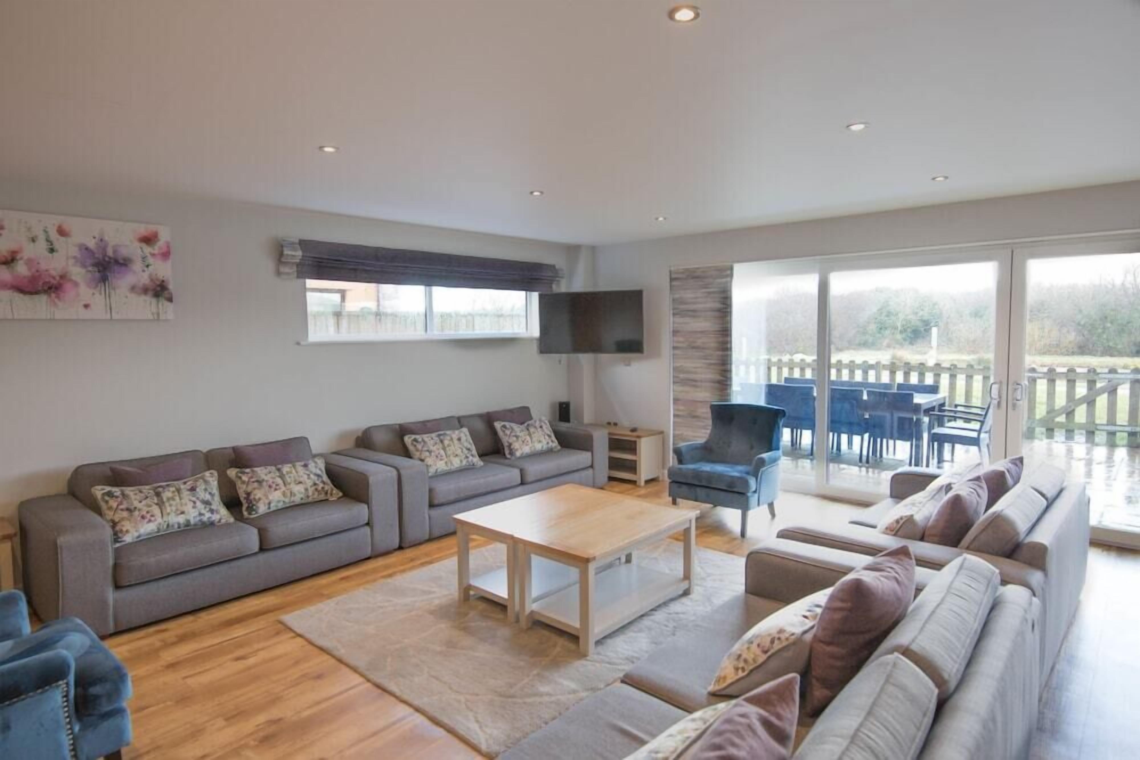 A spacious living room with a grey sofa set, a wooden coffee table, and a blue armchair.