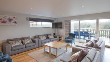 A spacious living room with a grey sofa set, a wooden coffee table, and a blue armchair.