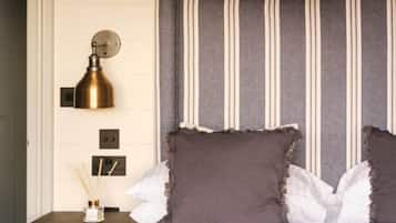 A neatly made bed with striped headboard, a bedside lamp, and a small table with a candle holder.