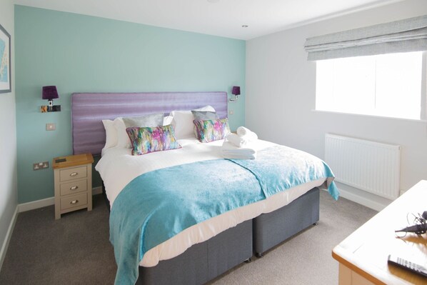 A neatly arranged bedroom with a bed, bedside tables, and a window with curtains. - Retallack Resort And Spa (St. Columb Major)