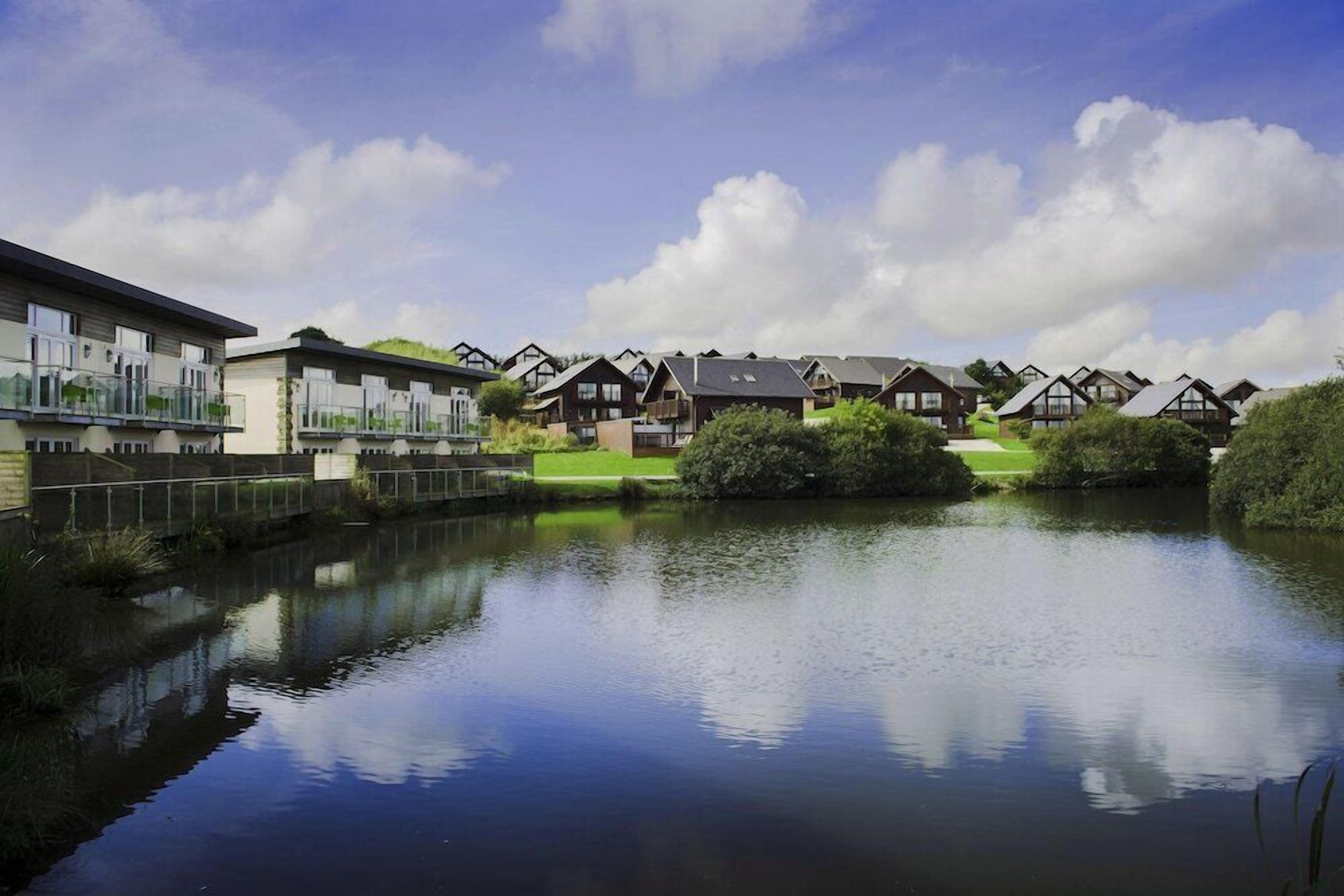 A lakeside residential area with modern and traditional houses, a calm lake, and a clear sky.