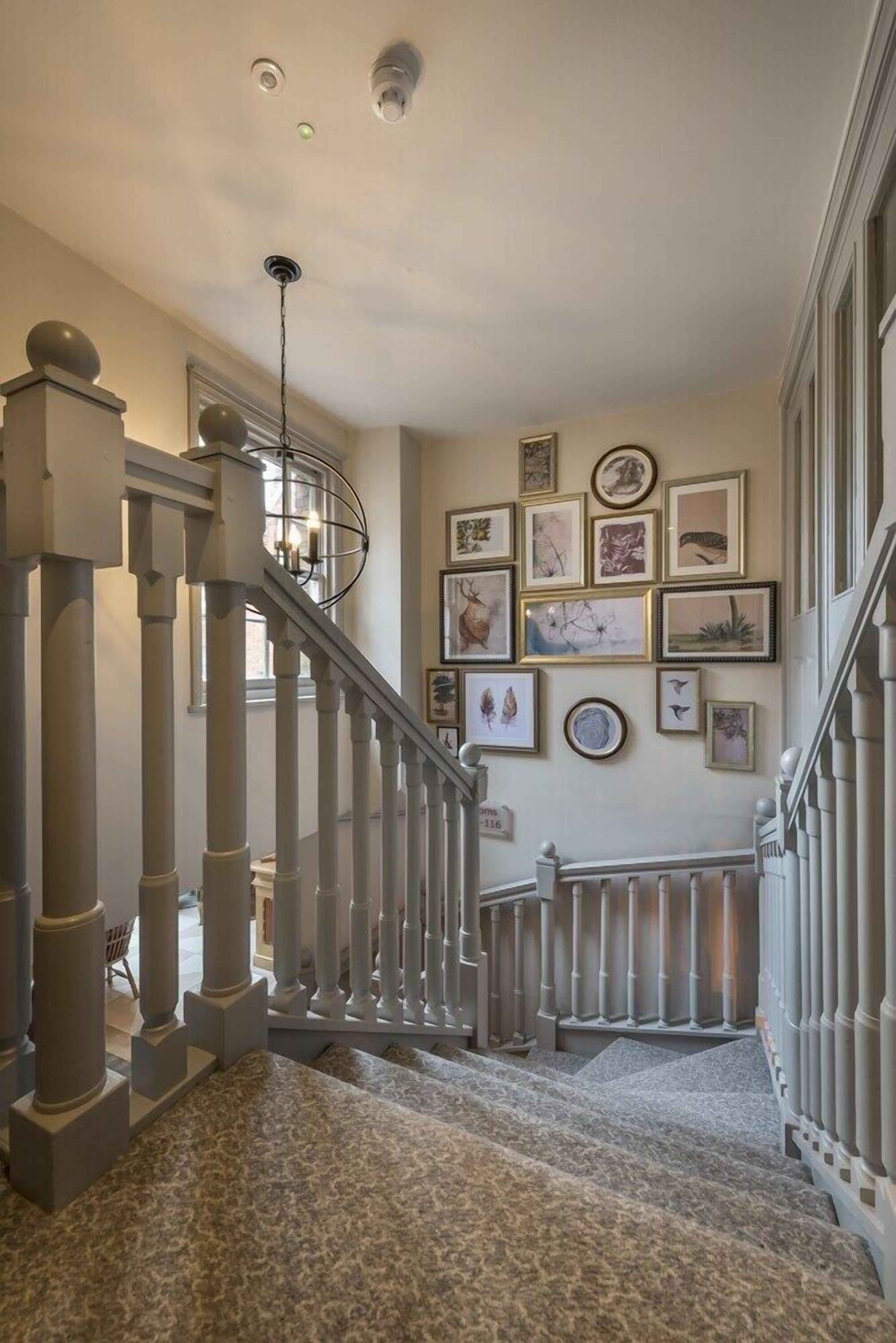 A staircase with a handrail, carpeted steps, and a wall adorned with framed artwork.