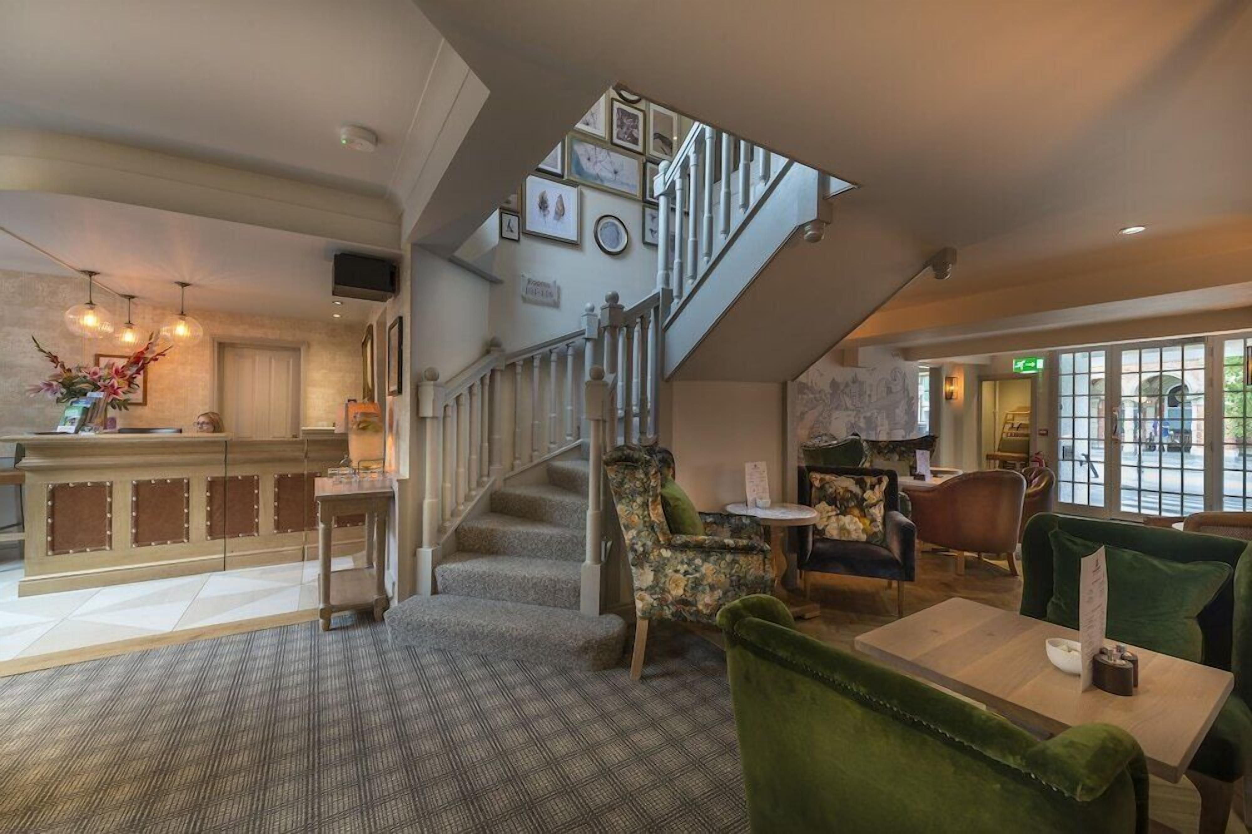 A hotel lobby with a staircase, seating area, and a reception desk.