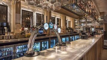 A bar area with multiple taps, including brands like Guinness and San Miguel, and a well-stocked shelf with various bottles.