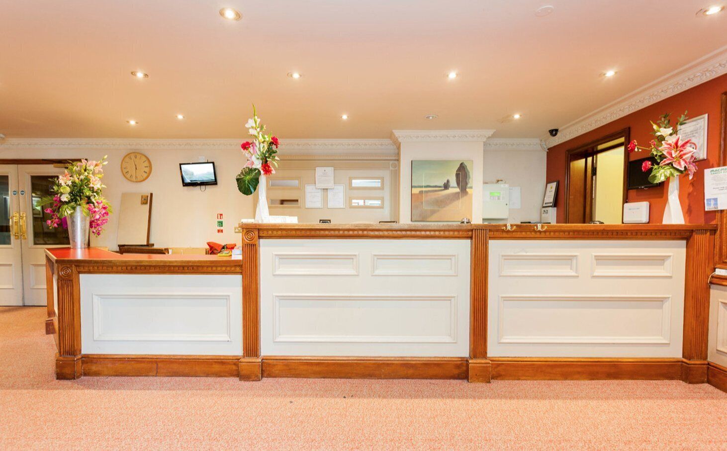 A reception desk with a clock, a television, and a bulletin board.