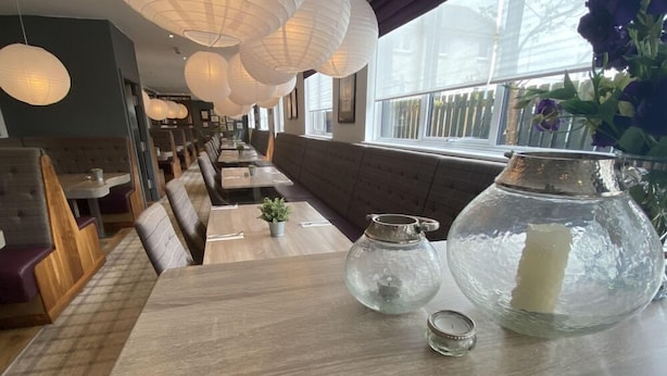 A restaurant interior with wooden tables, cushioned booths, hanging paper lanterns, and a large window with a view of the outside. - Craigiebield House Hotel (Penicuik)