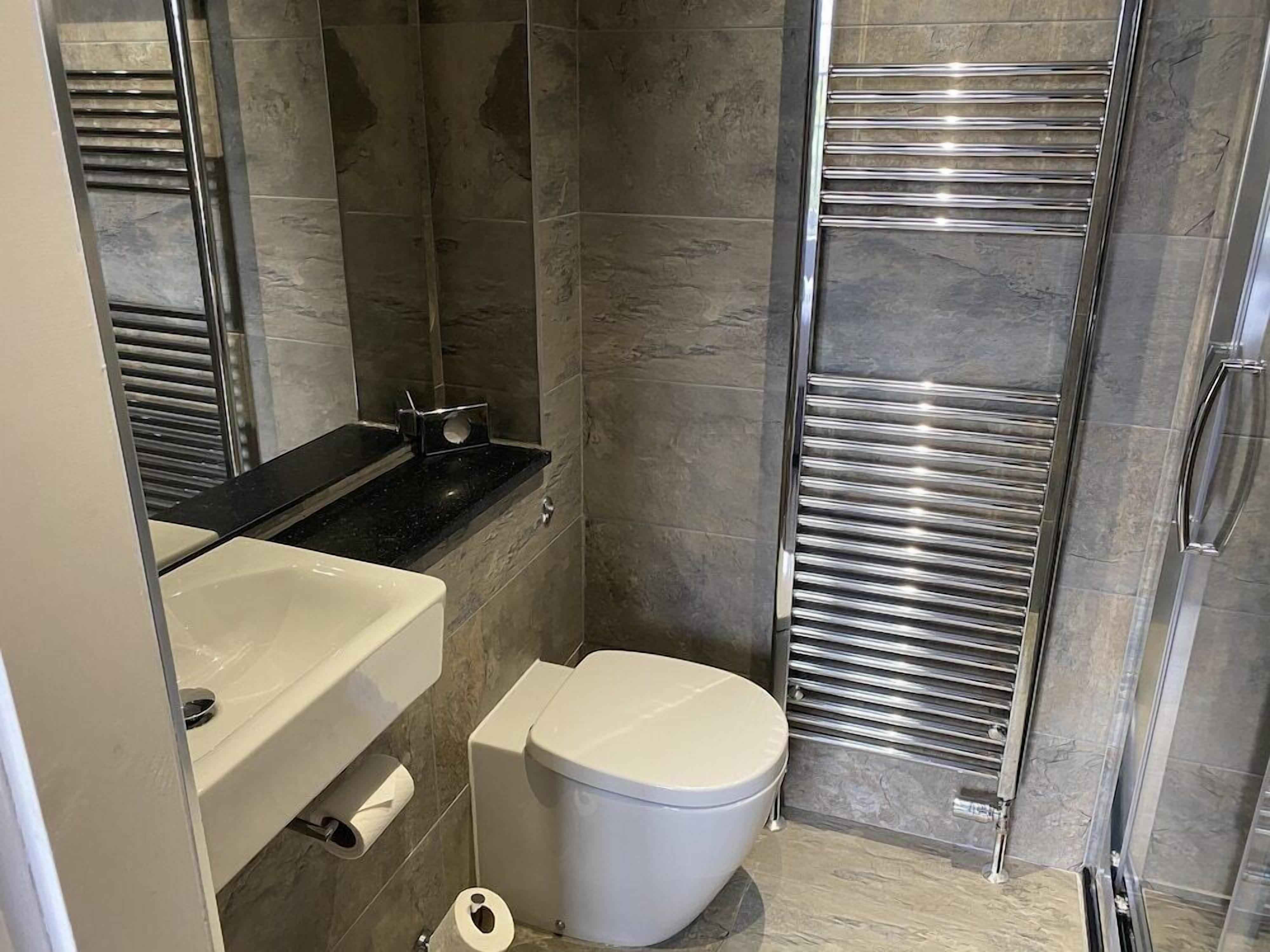A modern bathroom with a toilet, sink, and shower area.