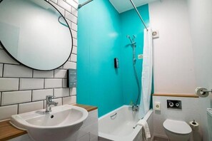 Kylpyhuone, jossa on valkoinen pesuallas, kylpyamme ja wc.