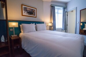 A neatly made bed with white linens, two bedside lamps, a framed picture on the wall, and a window with curtains. - Best Western Middlesbrough (Middlesbrough)